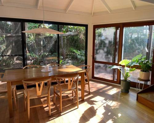 a dining room with a wooden table and chairs at The Tree House Byron Bay in Byron Bay