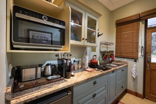 a kitchen with a sink and a microwave at Kambaku River Lodge in Malelane