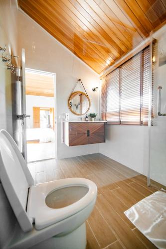 Un baño con un inodoro blanco y un espejo. en Thara Dara Khaoyai, en Ban Tha Maprang