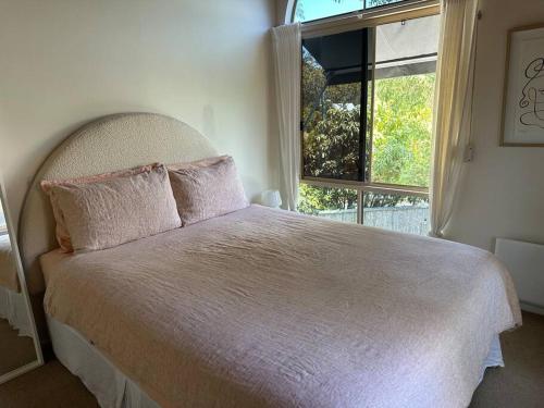 a bedroom with a large bed with a window at The Tree House Byron Bay in Byron Bay