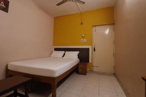 a small bedroom with a bed and a yellow wall at The Royal Comfort in Bangalore