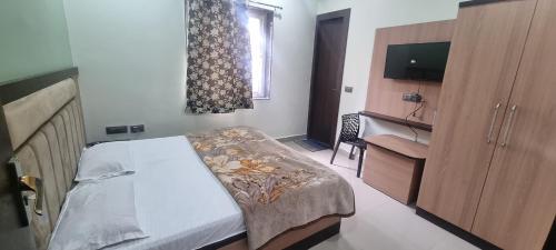 a bedroom with a bed and a dresser and a television at Saraswati Dhaam in Vrindāvan