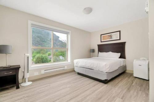 a white bedroom with a bed and a window at Scenic 3BR Penthouse Suite w/ Rooftop Lake View in Harrison Hot Springs