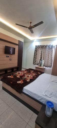 a bedroom with a large bed and a tv at Saraswati Dhaam in Vrindāvan