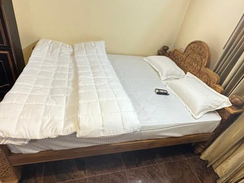 a bed with white sheets on it in a room at Mookambika tower room in Tiruvannāmalai
