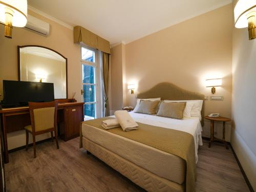 a bedroom with a bed and a desk and a television at Hotel Scapolatiello in Cava deʼ Tirreni