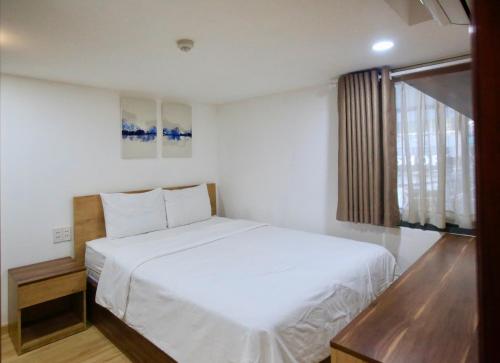 a bedroom with a white bed and a window at Cityhouse - Nguyễn Đình Chiểu in Ho Chi Minh City