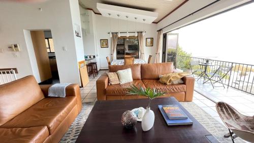 ein Wohnzimmer mit einem Sofa und einem Tisch in der Unterkunft Sea-View Family Villa in Gordonʼs Bay