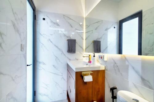 a white bathroom with a sink and a mirror at La Casa Deluxe - short escape from pererenan beach in Munggu