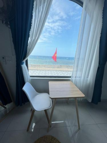 a table and a chair in front of a window with the beach at Vile Villa Homestay View Biển 01 Đảo Phú Quý in Cu Lao Thu
