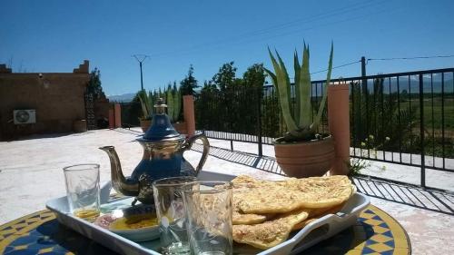 una mesa con una bandeja de comida con pan y un hervidor de agua. en Chez Kossai Atlas Farm, en Chtawna