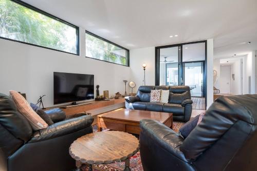 a living room with leather furniture and a flat screen tv at Ti Tree House - Live like a Bonbeach Local in Melbourne