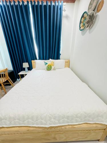 a bed in a room with a blue curtain at Vile Villa Homestay View Biển 01 Đảo Phú Quý in Cu Lao Thu
