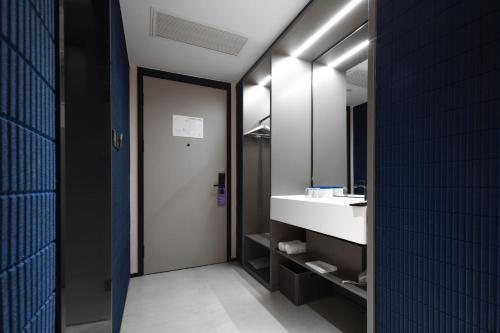 La salle de bains est pourvue d'un lavabo et d'un miroir. dans l'établissement Atour Light Hotel Huzhou Deqing Moganshan, à Deqing