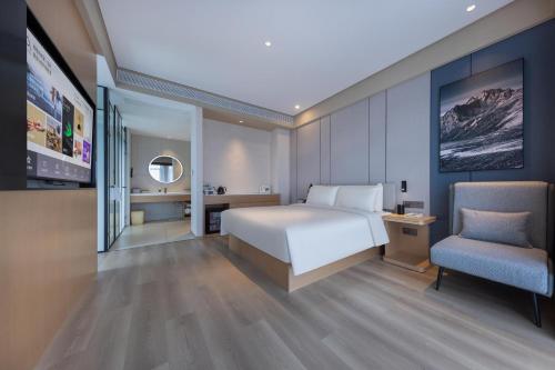 ein Schlafzimmer mit einem weißen Bett und einem Stuhl in der Unterkunft Atour X Hotel Nanjing Jiangning Future Internet Town in Jiangning