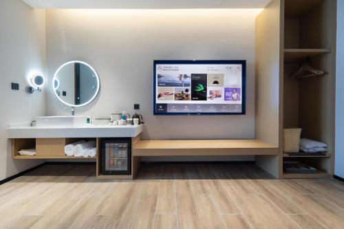ein Bad mit einem Waschbecken und einem TV an der Wand in der Unterkunft Atour X Hotel Haikou International Trade Center in Haikou