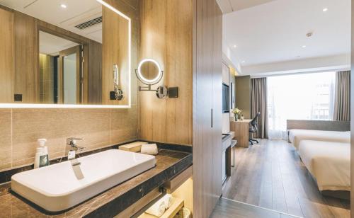 baño con lavabo, cama y espejo en Atour Hotel Ningbo Airport Yinzhou Avenue, en Ningbo