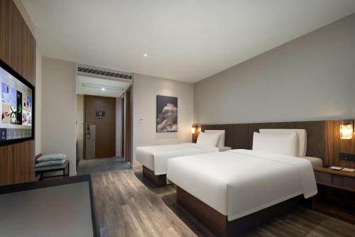 a hotel room with two beds and a flat screen tv at Atour X Hotel Hangzhou Binjiang Torch Avenue in Hangzhou