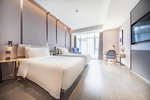 een hotelkamer met 2 bedden en een televisie bij Atour Hotel Ningbo Yinzhou Wanda Mingzhouli in Ningbo