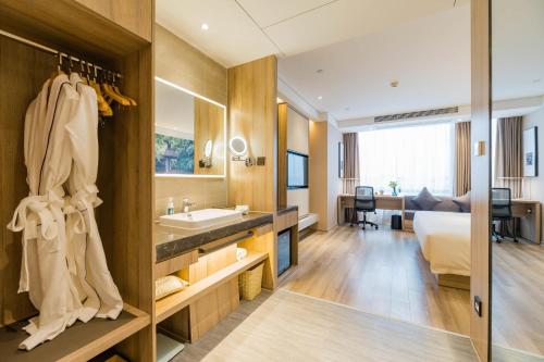 a bathroom with a sink and a bed in a room at Atour Hotel Changjiang North Road Wuxi in Wuxi