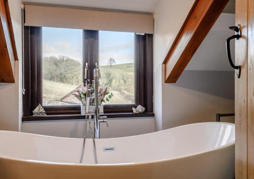 La salle de bains est pourvue d'une baignoire et d'une fenêtre. dans l'établissement Beacons View Farm Cottages, à Merthyr Cynog