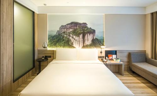 een slaapkamer met een groot bed en een muurschildering van de bergen bij Atour Hotel Foshan Nanhai Qiandeng Lake Guicheng in Nanhai