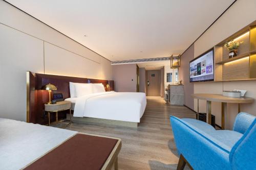 ein Hotelzimmer mit einem großen Bett und einem TV in der Unterkunft Atour X Hotel Haikou International Trade Center in Haikou