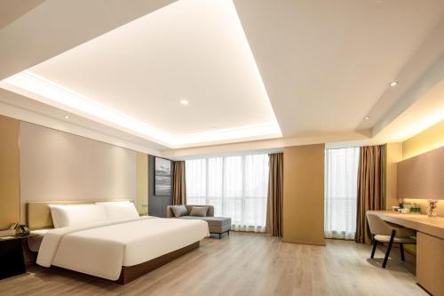 Schlafzimmer mit einem weißen Bett und einem Schreibtisch in der Unterkunft Atour X Hotel Wuxi Sanyang Plaza Zhongshan Road in Wuxi