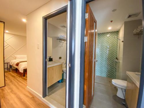 a bathroom with a shower and a toilet and a bed at Wesfame Suites in Manila