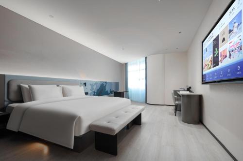 a bedroom with a large bed and a flat screen tv at Atour Light Hotel Huzhou Deqing Moganshan in Deqing