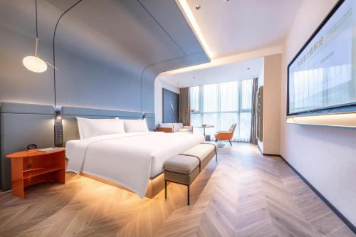 a hotel room with a large bed and a desk at Atour S Hotel Ningbo Binjiang Olympic Sports Center in Ningbo