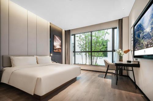 Atour Hotel Chengdu Jinhua Wanda Liulichang في تشنغدو: غرفة نوم بسرير ومكتب وتلفزيون