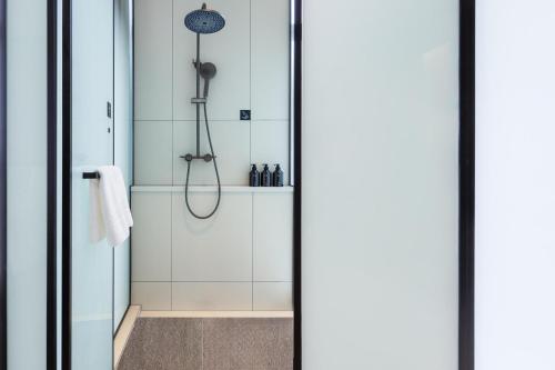 a shower in a bathroom with white tiles at Atour X Hotel Nanjing Jiangning Future Internet Town in Jiangning