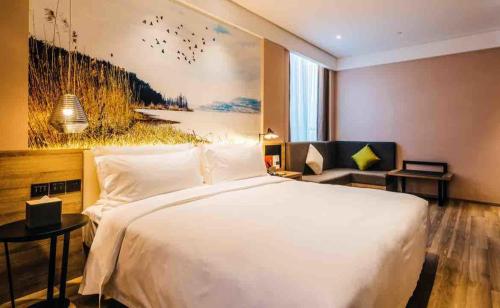 Atour Hotel South Business Zone Ningbo في نينغبو: غرفة نوم بسرير كبير ولوحة كبيرة