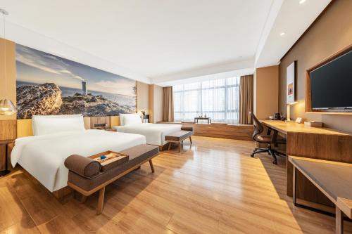 Cette chambre comprend un lit et un bureau. dans l'établissement Atour Hotel High Speed Railway Station Maoming, à Maoming