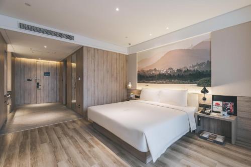 una camera da letto con un letto bianco e un quadro sul muro di Atour Hotel Nanjing South Station a Nanjing