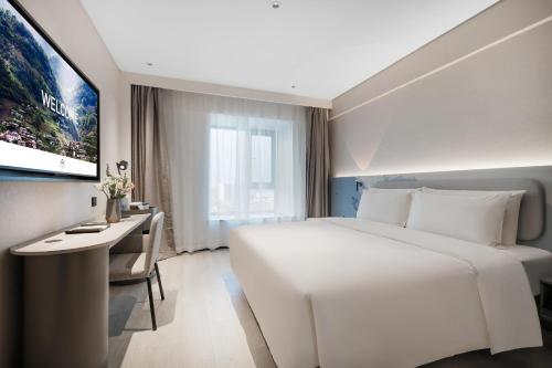 um quarto de hotel com uma grande cama branca e uma secretária em Atour Light Hotel Chengdu Shuangliu Airport Jinhua Road em Chengdu