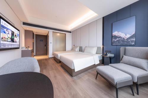 ein Hotelzimmer mit einem Bett und zwei Stühlen in der Unterkunft Atour X Hotel Guangzhou Avenue South Pazhou Convention and Exhibition Center in Guangzhou