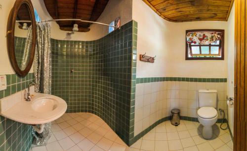 a green tiled bathroom with a sink and a toilet at Pousada Aldeia in Ilha de Boipeba