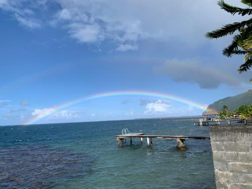 un arco iris sobre un cuerpo de agua con muelle en ATITAUTU Guest House, en Tautira