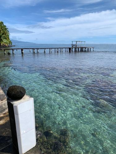 un muelle en el agua junto al océano en ATITAUTU Guest House, en Tautira