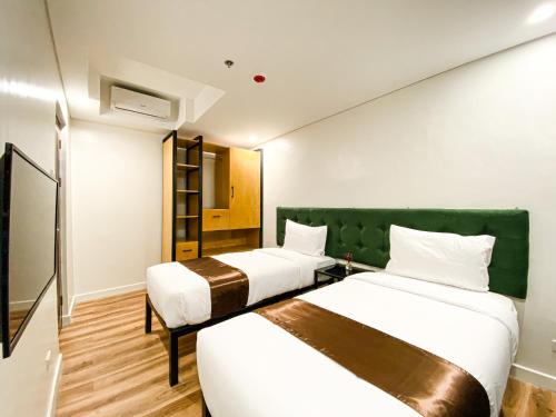 um quarto de hotel com duas camas e uma cabeceira verde em Wesfame Suites em Manila