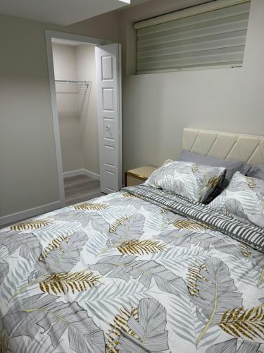 a bedroom with a bed with a leaf patterned blanket at Brand new 2 Bedrooms modern guest suite with separate entrance in Calgary