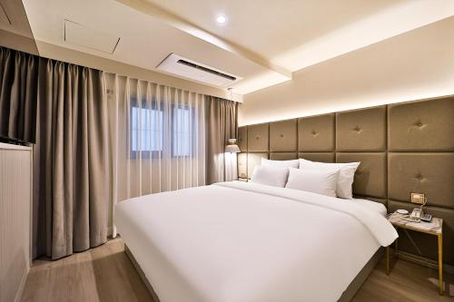 1 cama blanca grande en una habitación de hotel en Denbasta Hotel Daeyeon en Busan