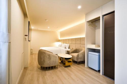Habitación de hotel con 1 cama y 2 sillas en Denbasta Hotel Daeyeon en Busan