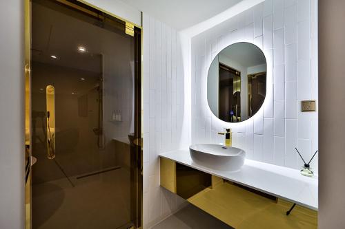 a bathroom with a sink and a mirror and a shower at Denbasta Hotel Daeyeon in Busan