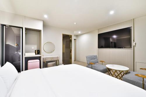 a hotel room with a large bed and chairs at Denbasta Hotel Daeyeon in Busan
