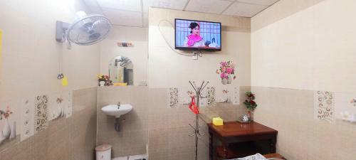 a bathroom with a sink and a tv on the wall at Nhà Nghỉ Xuân Lan in Ấp An Mỹ