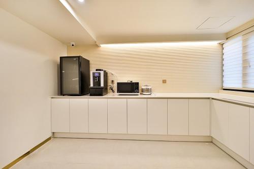 a kitchen with white cabinets and a black appliance at Denbasta Hotel Daeyeon in Busan
