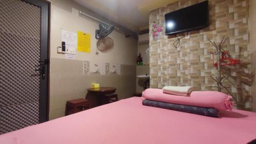 a room with a pink bed with a tv on the wall at Nhà Nghỉ Xuân Lan in Ấp An Mỹ